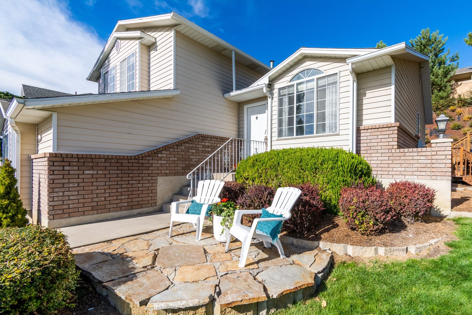 Home Elegant suburban house exterior with porch and seating area in bright daylight.